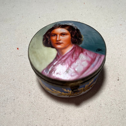 Cajita redonda de porcelana Bidasoa con retrato de maja pintado a mano en la tapa, cerco dorado y banda decorativa con laurel y ánfora sobre fondo azul.