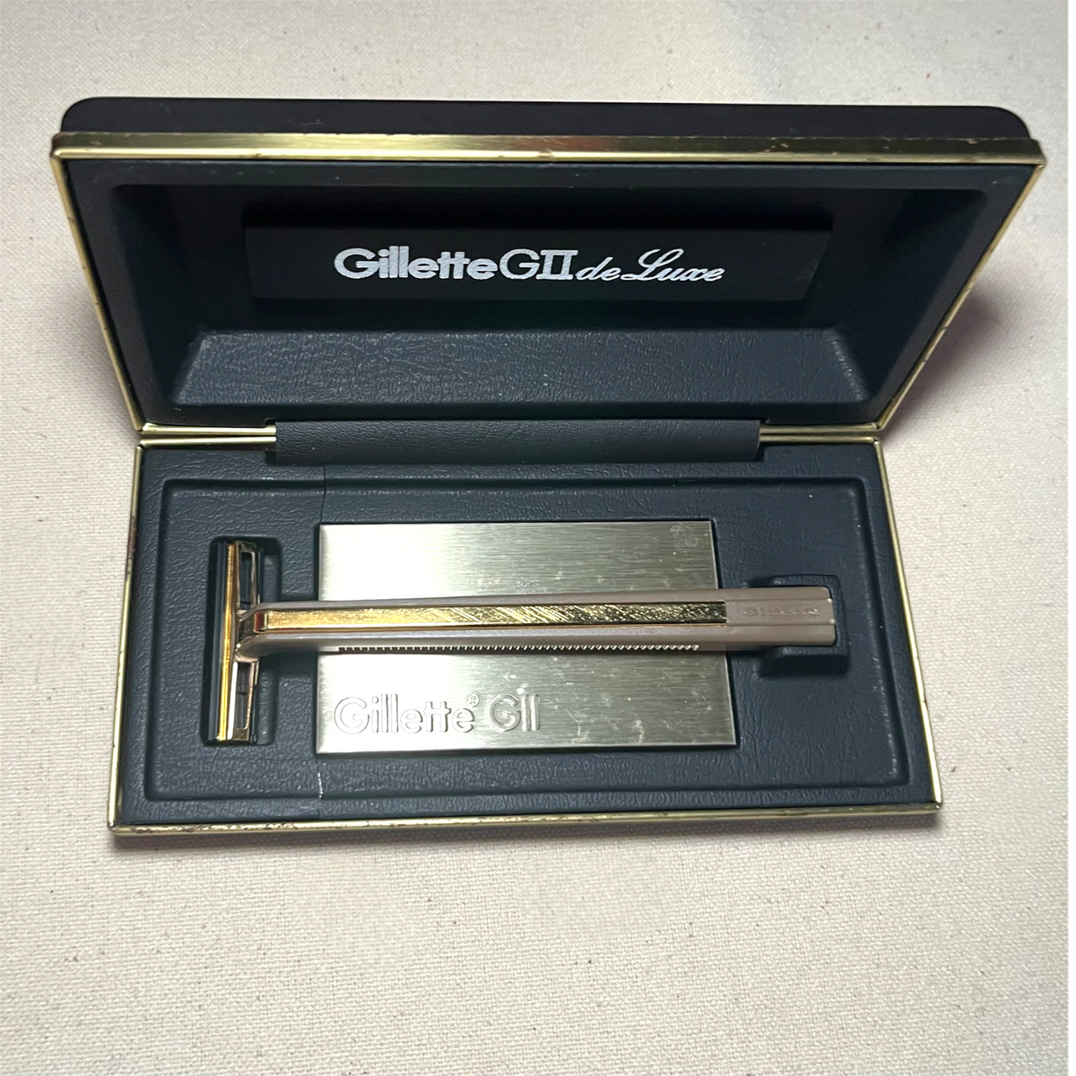 Maquinilla de afeitar Gillette GII De Luxe en su estuche azul noche abierto, con libreto de instrucciones.