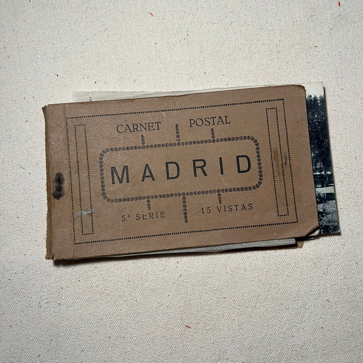 Carnet de postales antiguas de Madrid, abierto, con las hojas separadas por papel de seda y la firma manuscrita en la primera página.