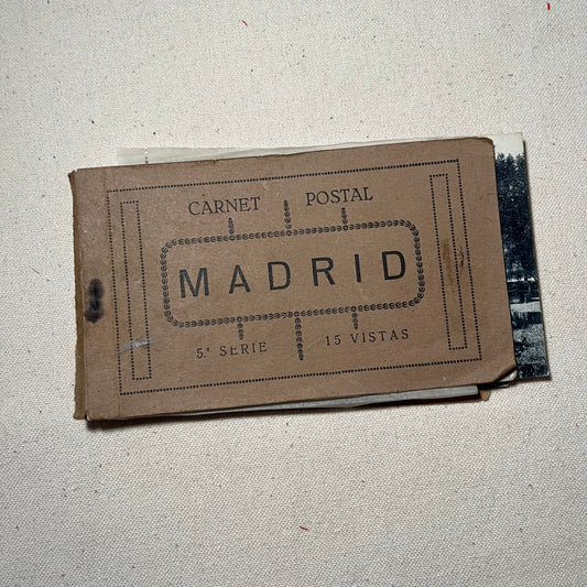 Carnet de postales antiguas de Madrid, abierto, con las hojas separadas por papel de seda y la firma manuscrita en la primera página.