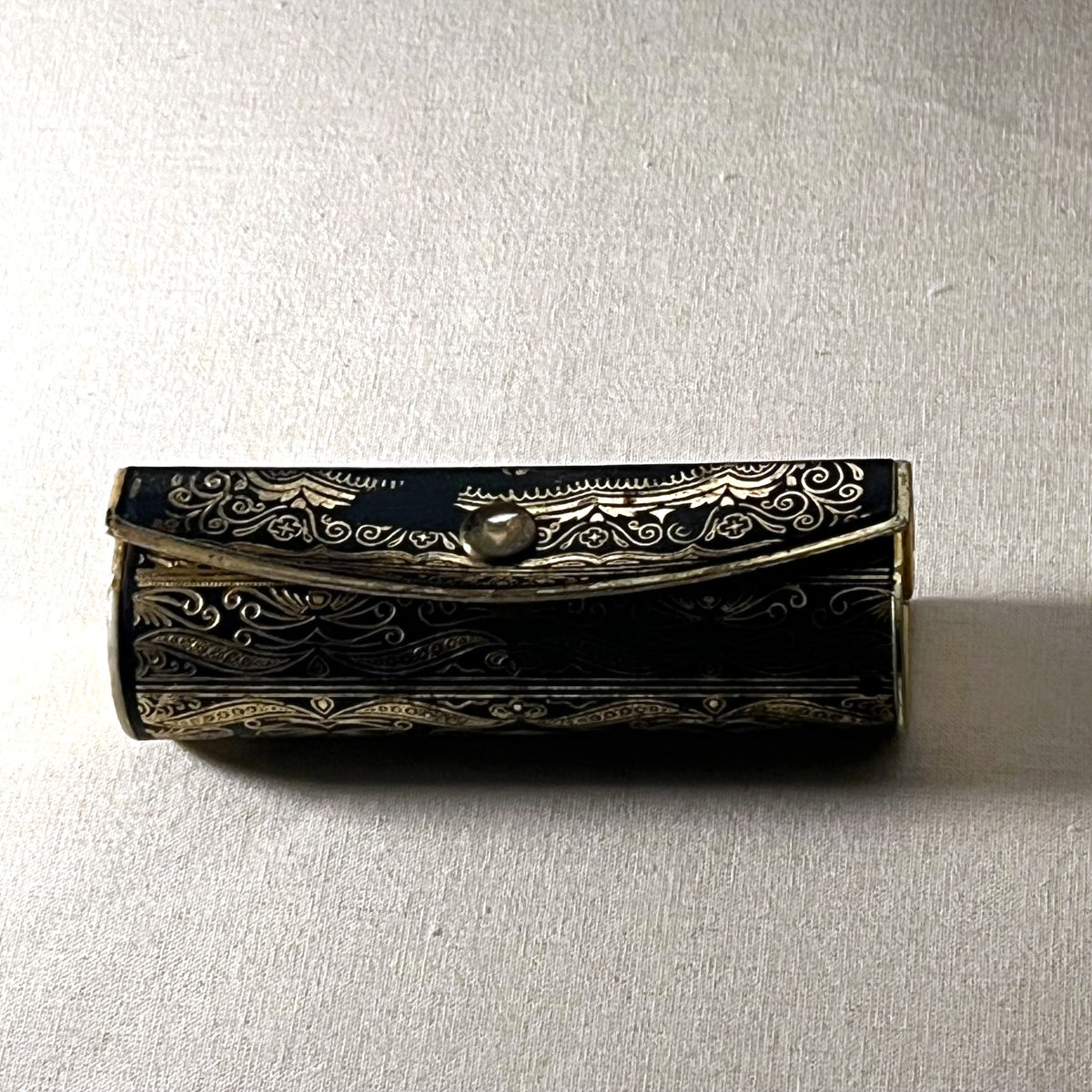 Estuche de pintalabios italiano con espejo, metal negro y dorado con volutas y flores, cerrado