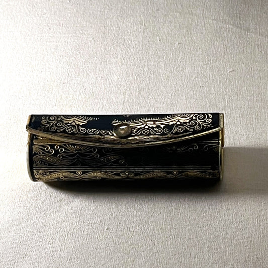 Estuche de pintalabios italiano con espejo, metal negro y dorado con volutas y flores, cerrado