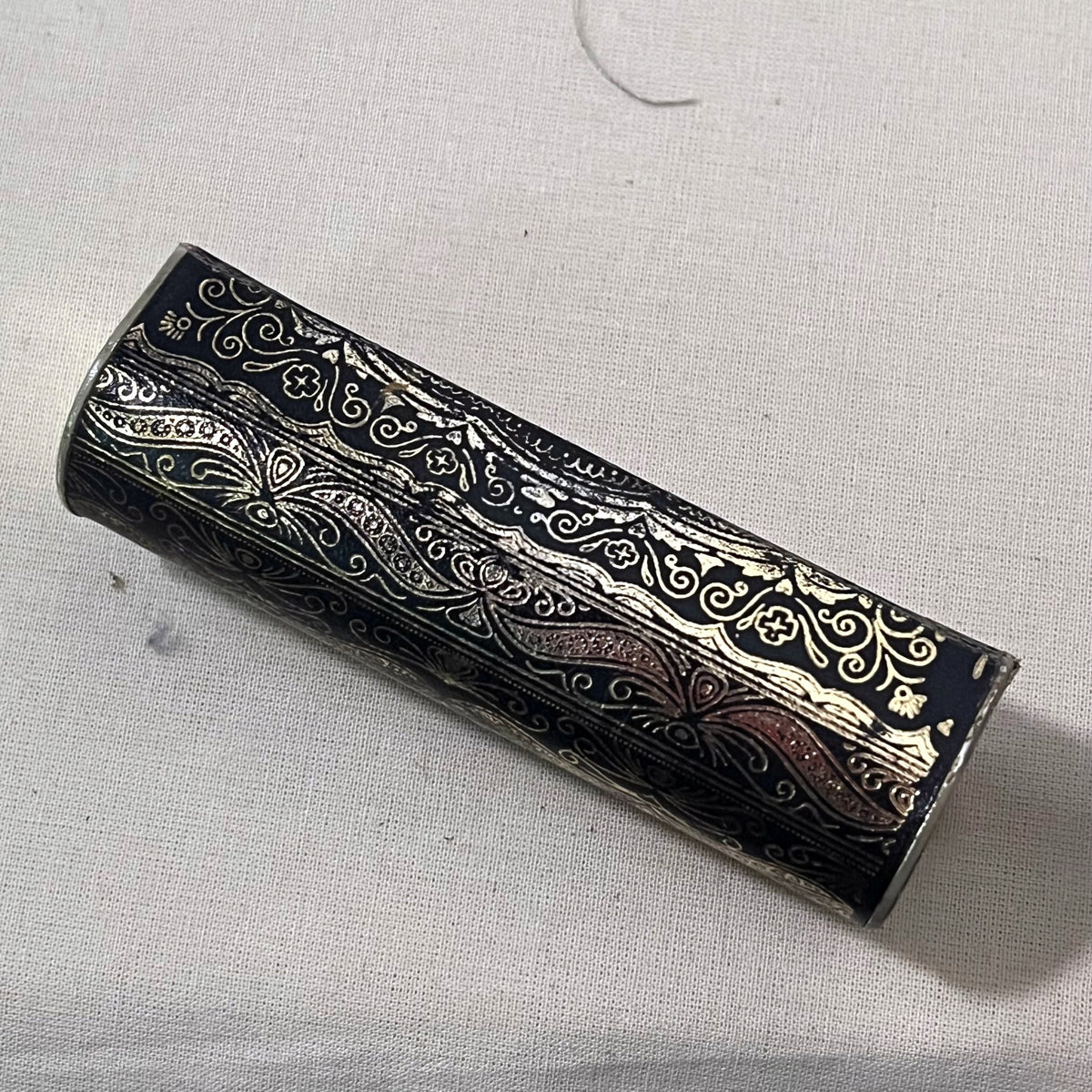 Reverso del estuche de pintalabios con el dorado gastado en las aristas
