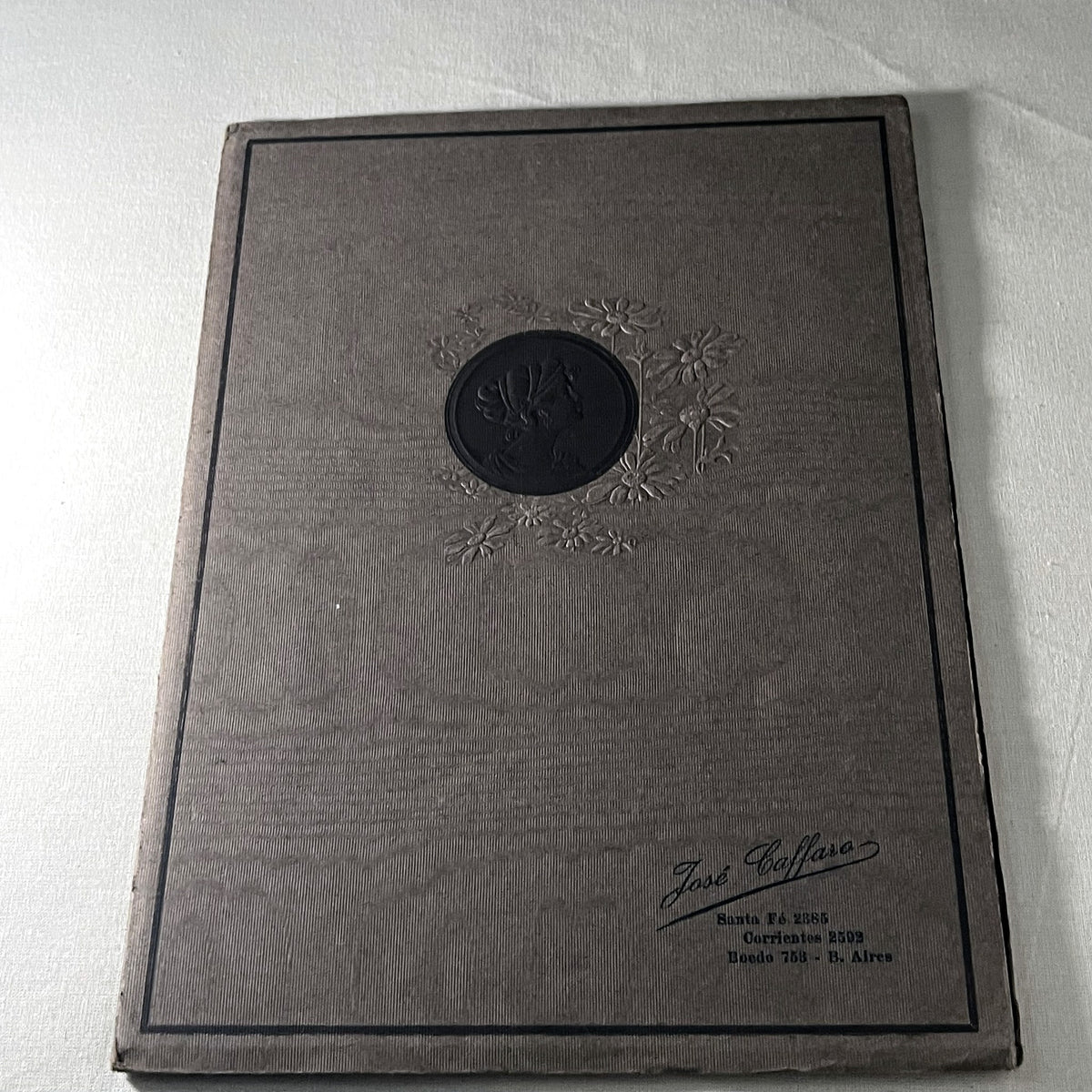 Carpeta de fotografía José Caffaro, Buenos Aires, cubierta muaré gris con medallón de dama y flores en relieve
