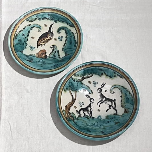 Pareja de platos de cerámica pintados a mano con liebres y una perdiz en tonos verdes, vista frontal